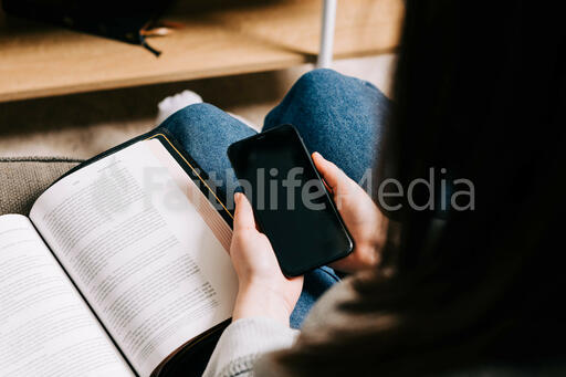 Woman Holding Her Phone and a Bible