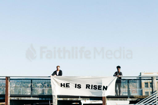 People Holding a He Is Risen Banner on a Rooftop