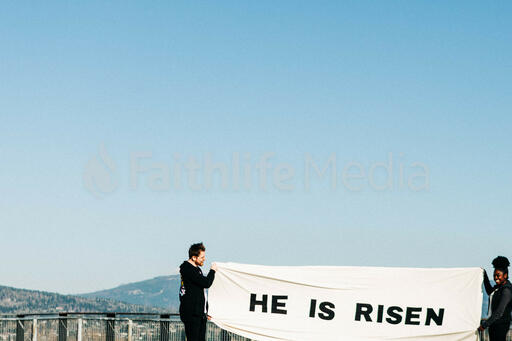 People Holding a He Is Risen Banner on a Rooftop