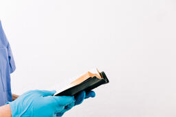 Hands with Gloves on Holding an Open Bible  image 1