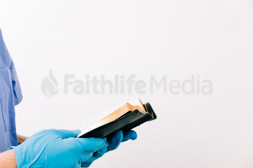 Hands with Gloves on Holding an Open Bible
