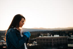 Woman Wearing Medical Gloves and Praying Over the City  image 4