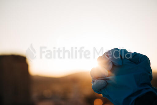 Woman Wearing Medical Gloves and Praying Over the City