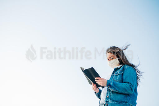 Woman Wearing a Face Mask and Reading the Bible