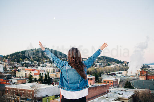 Woman with Hands Raised in Worship on a Rooftop