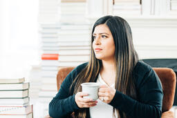 Woman Drinking Coffee Surrounded by Books  image 1