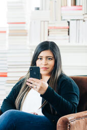A Woman Studying on an iPhone in a Living Room Full of Books  image 9