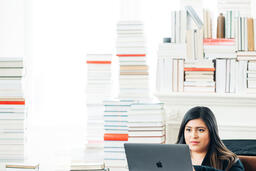 Woman Studying on a Laptop in a Living Room Full of Books  image 4