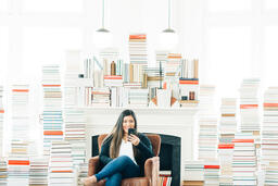 A Woman Studying on an iPhone in a Living Room Full of Books  image 1