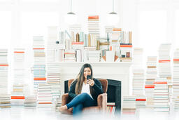 A Woman Studying on an iPhone in a Living Room Full of Books  image 4