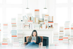 A Woman Studying on an iPad in a Living Room Full of Books  image 1