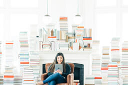 A Woman Studying on an iPad in a Living Room Full of Books  image 3