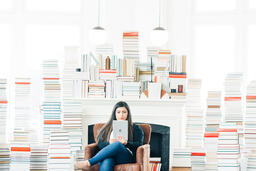 A Woman Studying on an iPad in a Living Room Full of Books  image 1