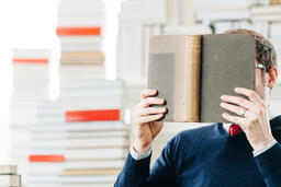 Man Reading a Book in a Living Room Full of Books  image 1