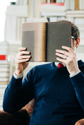 Man Reading a Book in a Living Room Full of Books  image 2