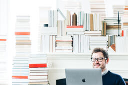 Man Studying on a Laptop in a Living Room Full of Books  image 13