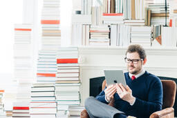 Man Studying on an iPad in a Living Room Full of Books  image 2