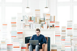 Man Studying on a Laptop in a Living Room Full of Books  image 2
