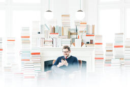 Man Studying on an iPhone in a Living Room Full of Books  image 3