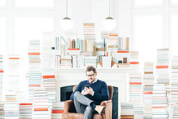 Man Studying on an iPhone in a Living Room Full of Books  image 4