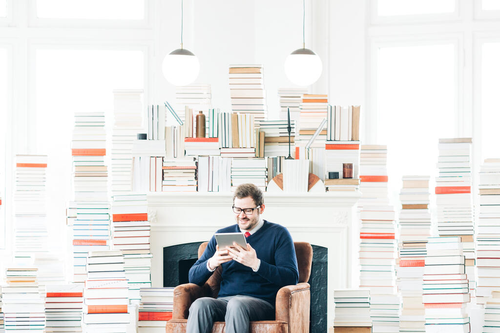 Man Studying on an iPad in a Living Room Full of Books large preview