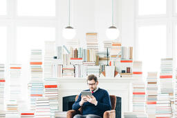 Man Studying on an iPad in a Living Room Full of Books  image 2