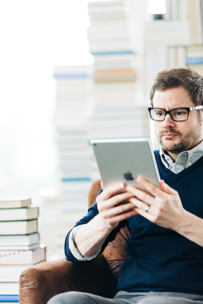 Man Studying on an iPad in a Living Room Full of Books large preview