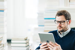 Man Studying on an iPad in a Living Room Full of Books  image 5