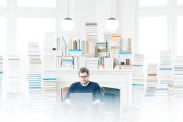 Man Studying on a Laptop in a Living Room Full of Books  image 2