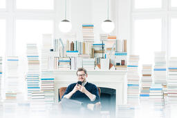 Man Studying on an iPhone in a Living Room Full of Books  image 2