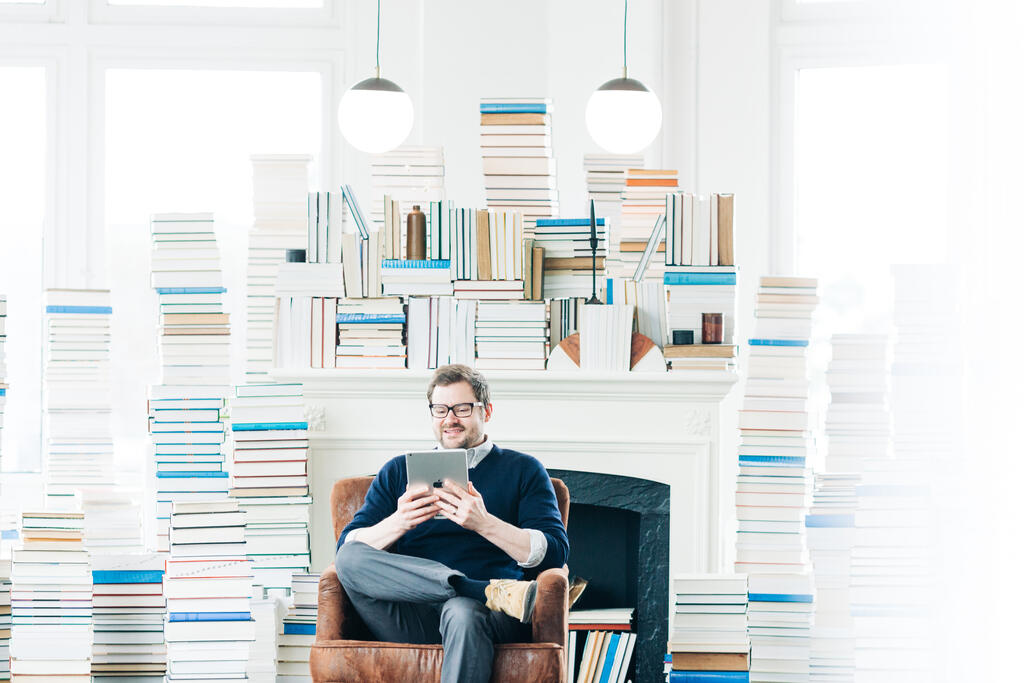 Man Studying on an iPad in a Living Room Full of Books large preview