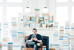 Man Studying on an iPad in a Living Room Full of Books  image 1