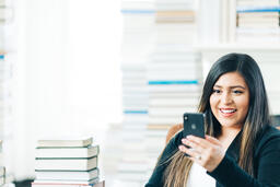 Woman Studying on an iPhone in a Living Room Full of Books  image 2