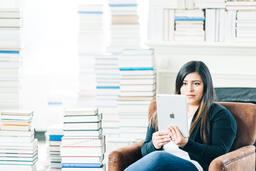 Woman Studying on an iPad in a Living Room Full of Books  image 1
