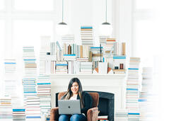 Woman Studying on a Laptop in a Living Room Full of Books  image 2