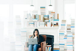 Woman Studying on a Laptop in a Living Room Full of Books  image 1