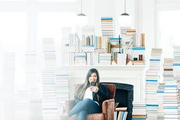 Woman Studying on an iPhone in a Living Room Full of Books  image 1