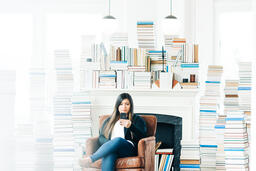 Woman Studying on an iPhone in a Living Room Full of Books  image 2
