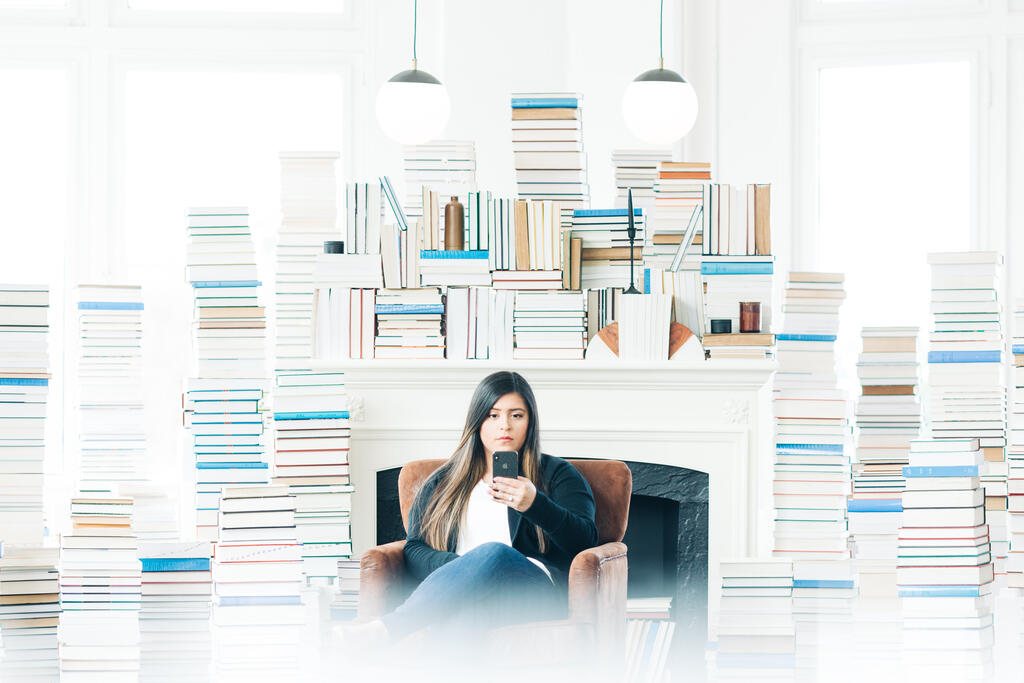 Woman Studying on an iPhone in a Living Room Full of Books large preview