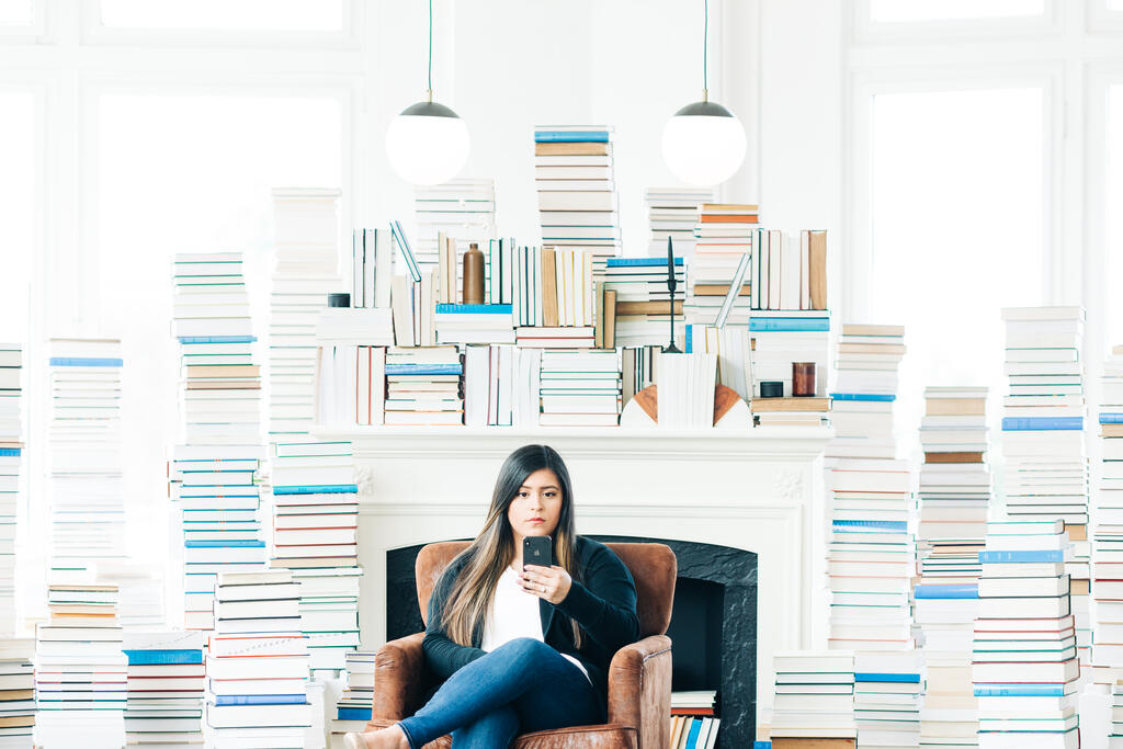 Woman Studying on an iPad in a Living Room Full of Books large preview