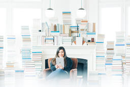 Woman Studying on an iPad in a Living Room Full of Books  image 2