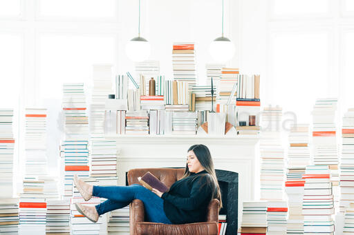A Woman Reading Surrounded by Stacks of Books