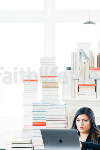 Woman Studying on a Laptop in a Living Room Full of Books