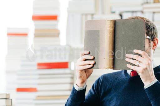 Man Reading a Book in a Living Room Full of Books