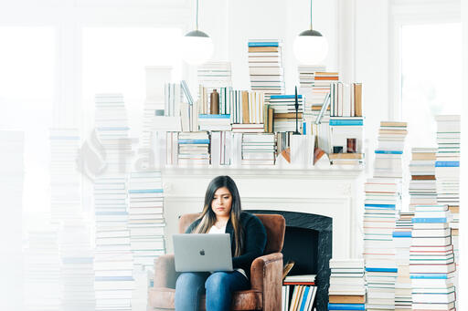 Woman Studying on a Laptop in a Living Room Full of Books