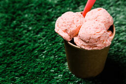 Carton of Strawberry Ice Cream with a Spoon on Grass  image 3