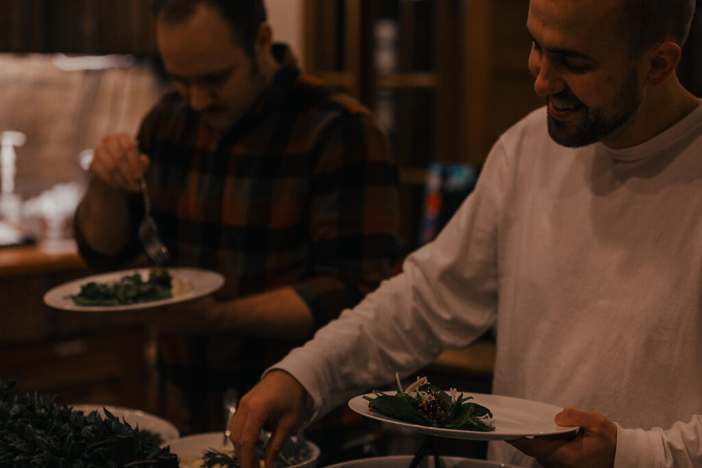 Man Serving Up Salad at a Potluck large preview