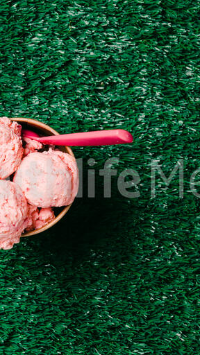 Carton of Strawberry Ice Cream with a Spoon on Grass