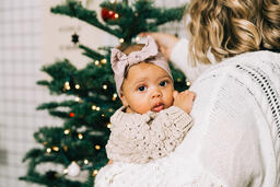 Woman Holding Her Baby and Decorating for Christmas  image 2