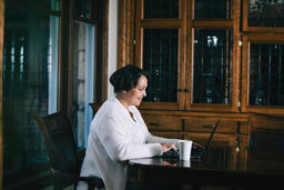 Woman Working on a Laptop with a Cup of Coffee at the Table  image 1